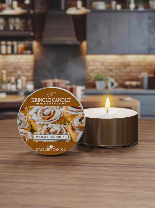 Kringle Candle candle Warm Cinnabuns DayLight Candle with packaging on a wooden surface.