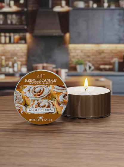 Kringle Candle candle Warm Cinnabuns DayLight Candle with packaging on a wooden surface.