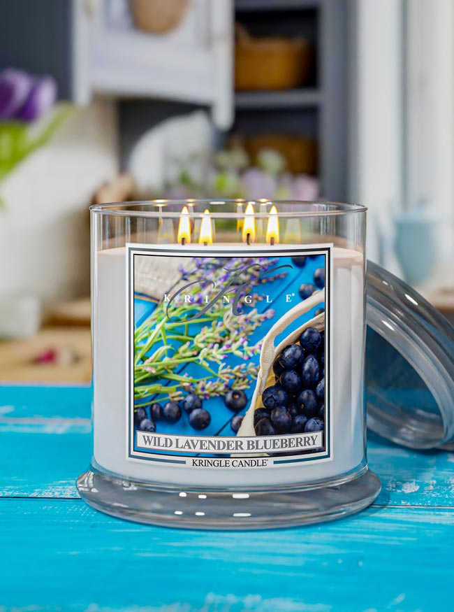 Kringle Candle Wild Lavender Blueberry candle on a blue surface with a blurred background